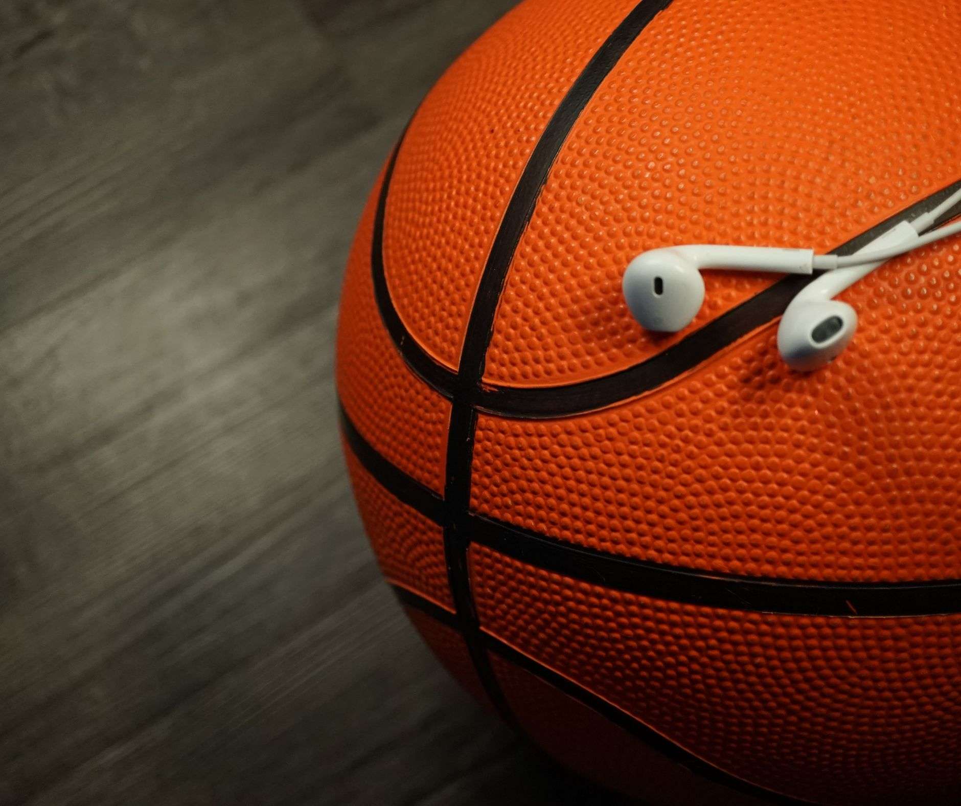 Foto decorativa. Pallone da basket con auricolari del telefono appoggiati sopra